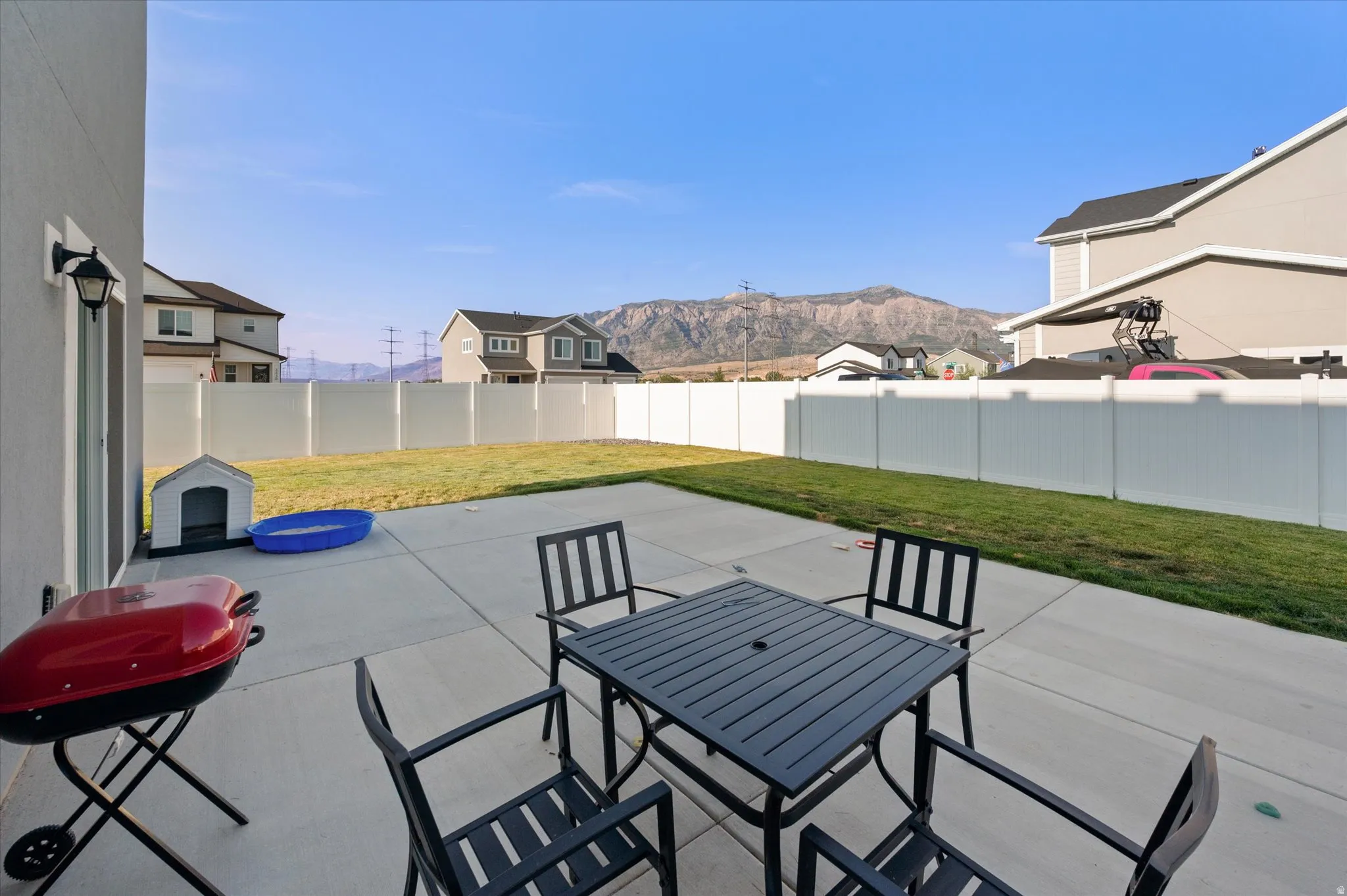 Expansive concrete patio with a full white privacy fence surrounding a grass lawn