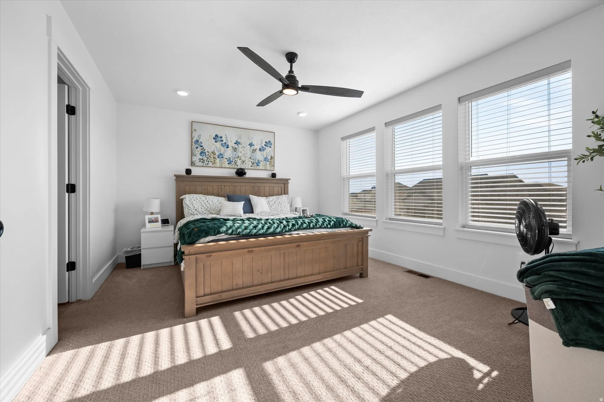 Carpeted room featuring multiple windows, a ceiling fan with integrated lighting, and recessed ceiling lights