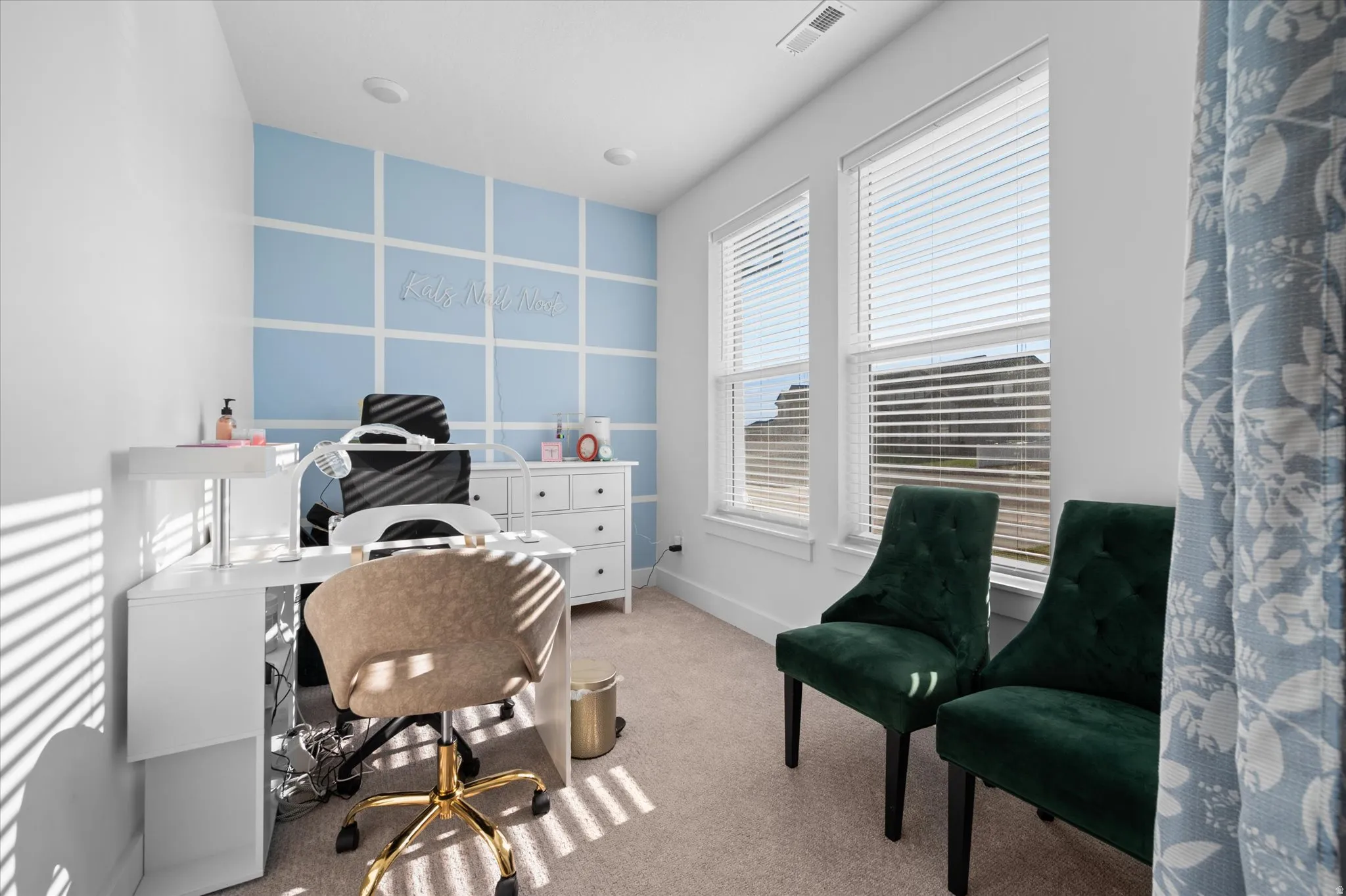 Recessed lighting, two bright windows with blinds, light wall-to-wall carpeting, and a decorative accent wall with grid paneling