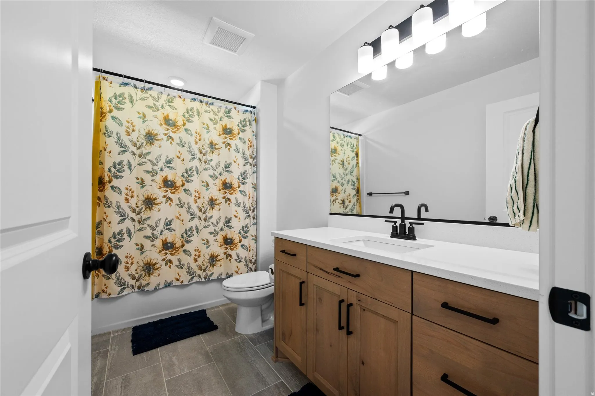 Modern bathroom featuring a wood-finish vanity with a white countertop and rectangular undermount sink