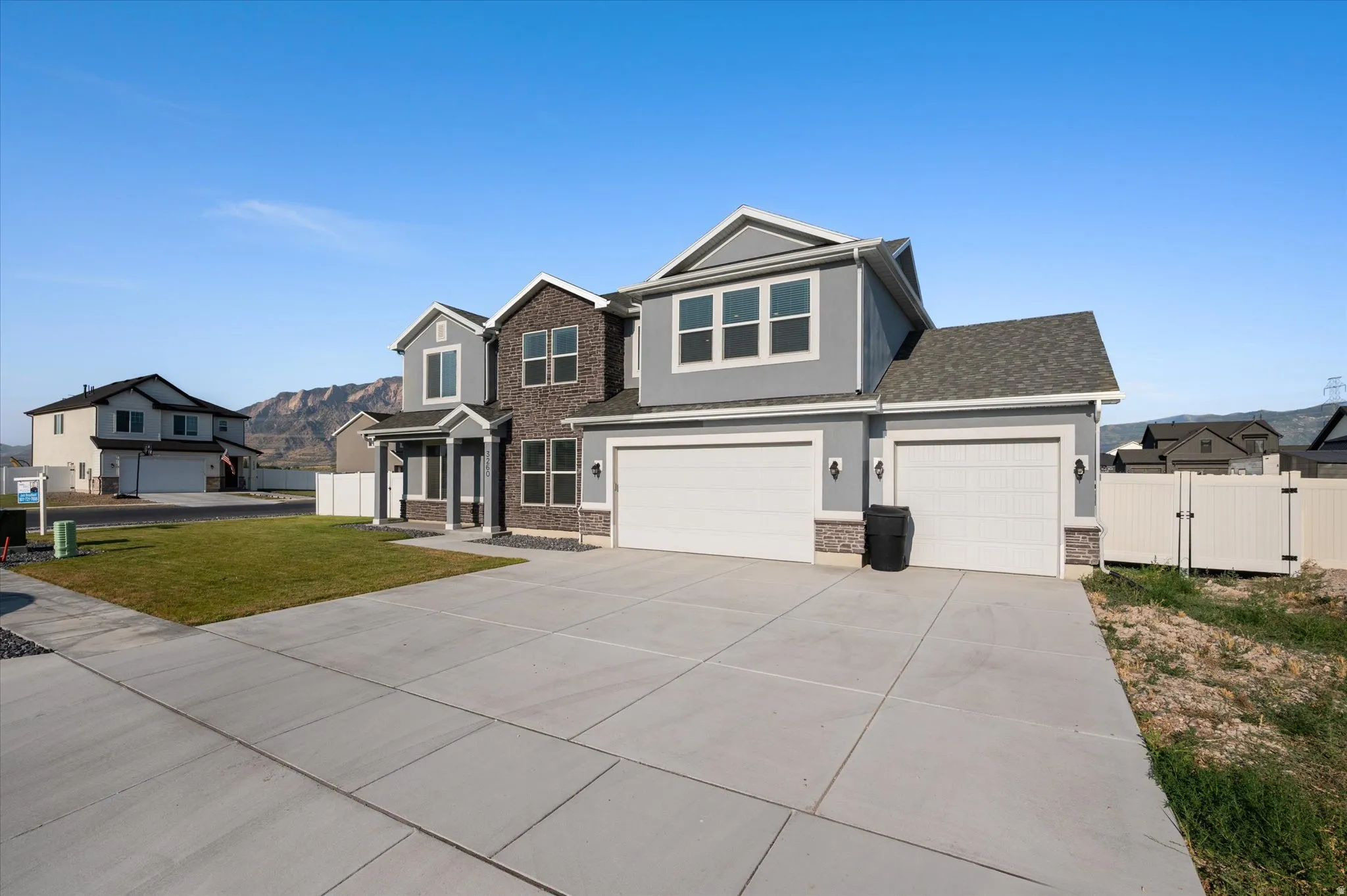 Contemporary residence featuring a two-car garage, stone and siding exterior, a covered entry, and a concrete driveway