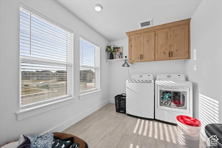 Laundry space featuring a mounted wooden cabinet, two windows with blinds, recessed ceiling lighting, and tiled flooring