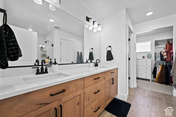 Dual vanity with wood-finish cabinetry, white countertops, and matte black fixtures
