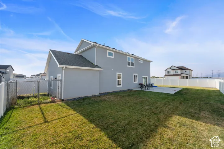 Spacious backyard with a concrete patio, expansive lawn, and a chain-link fence