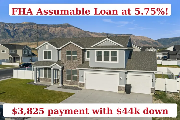 Modern gray exterior with stone veneer accents, multi-pane windows, attached dual garage, paved driveway, and a manicured lawn