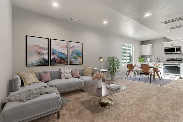Open-concept living space with recessed lighting, light-toned carpeting, and a kitchen featuring white cabinetry, stainless steel appliances, and wood-finish flooring