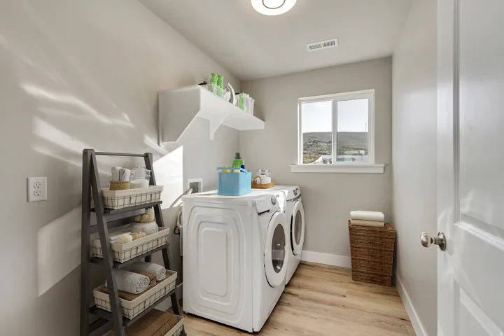 Dedicated laundry area featuring wood-finish flooring, a bright window, and wall-mounted shelving