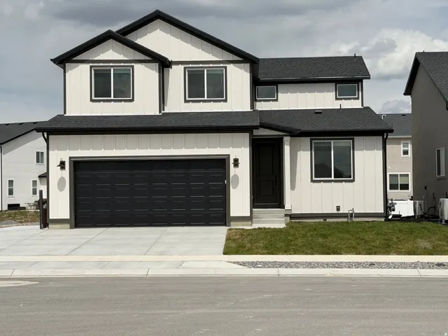 Modern two-story residence featuring a two-car garage, white vertical board-and-batten siding with black trim, and a concrete driveway