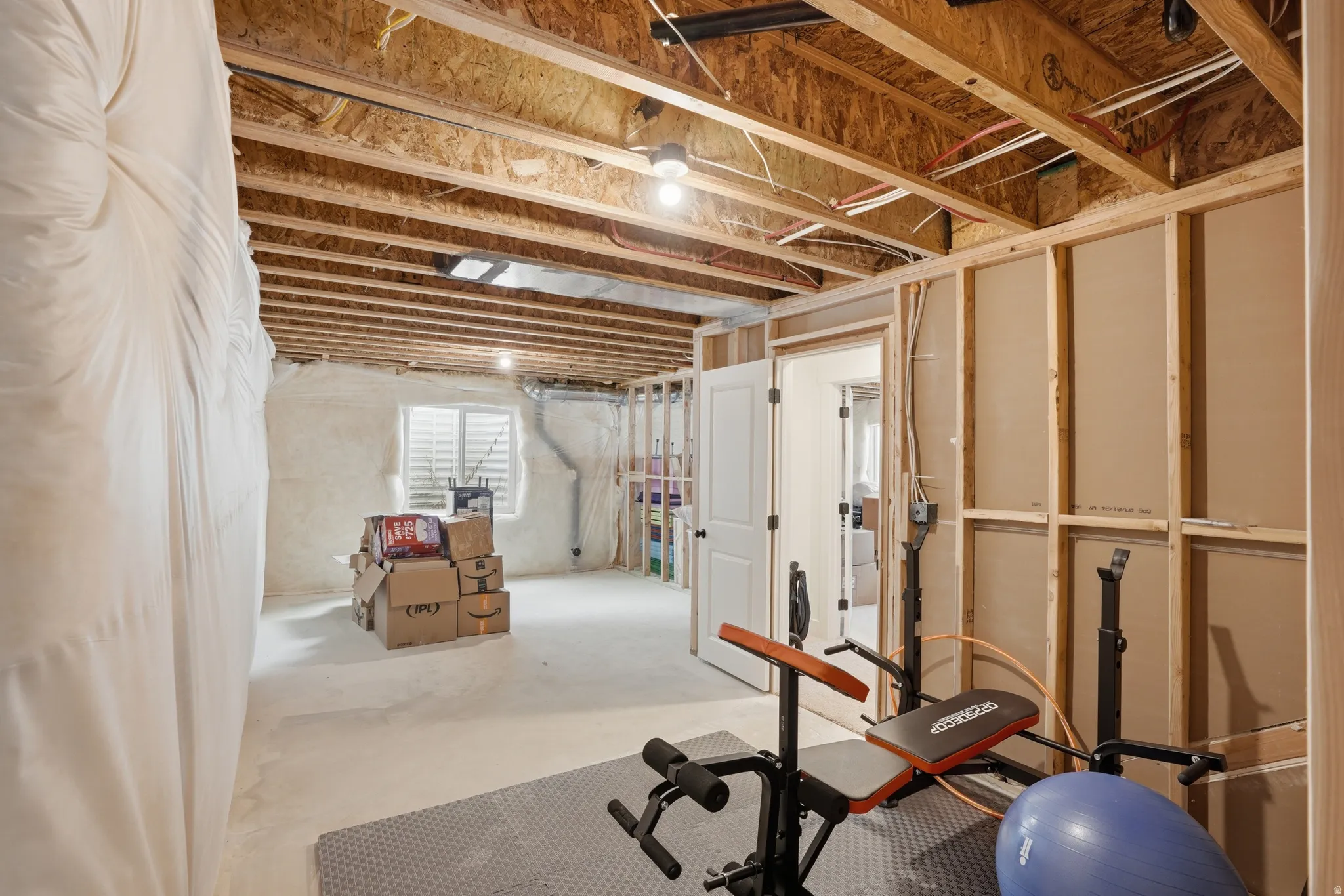 Unfinished basement space featuring exposed wood joists and structural framing