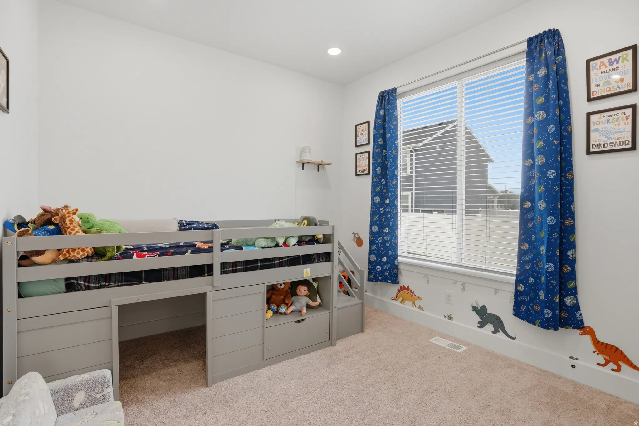 Bright room featuring a large window with horizontal blinds, neutral wall paint, and light-toned carpet flooring