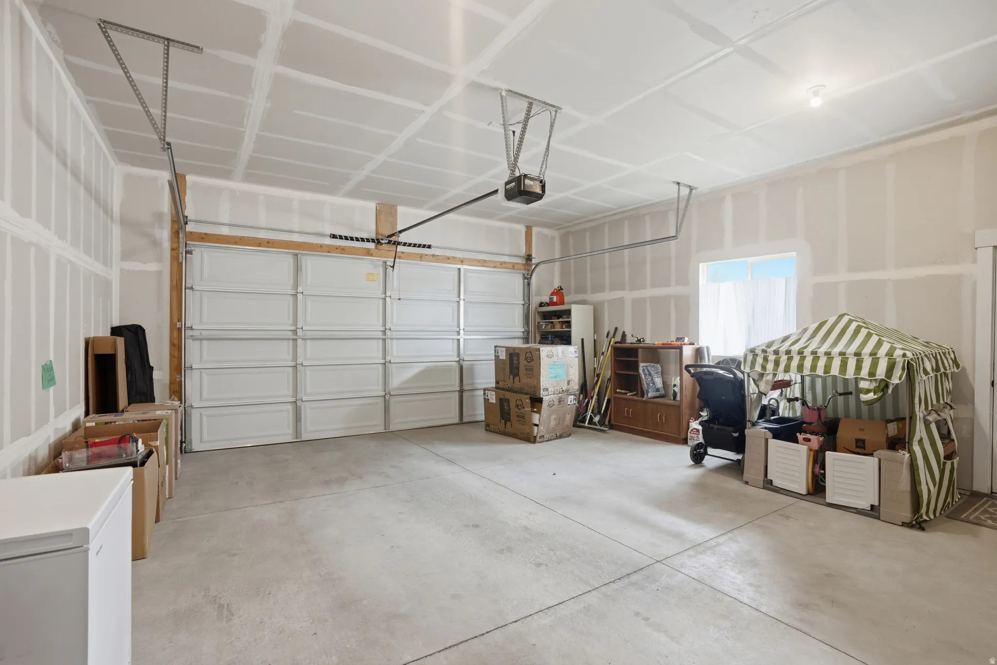 Spacious garage featuring a concrete floor, overhead lighting, and an automatic garage door opener
