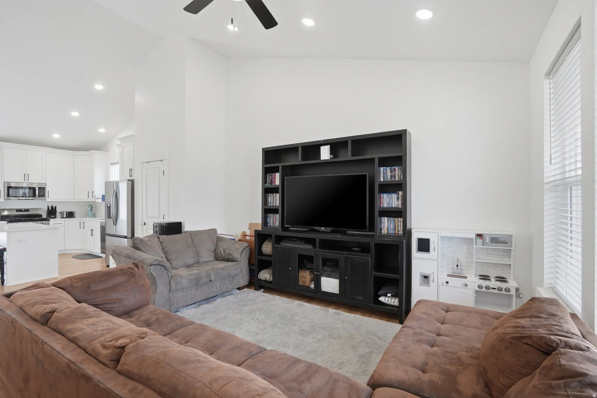 Open-concept living space featuring high ceilings with recessed lighting, a ceiling fan, and light wood-finish flooring