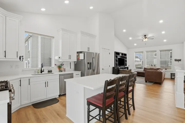Open-concept interior featuring a kitchen with white cabinetry, stainless steel appliances, and a central island with bar seating