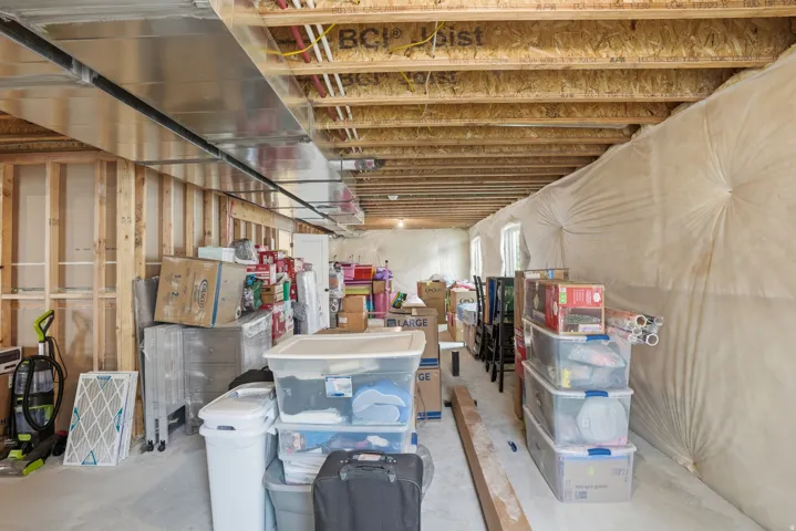 Unfinished basement featuring exposed wood joists, structural framing, and concrete flooring