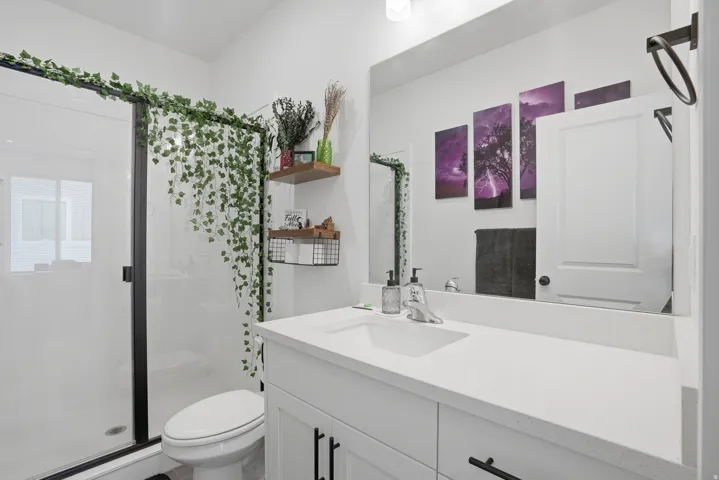 Bathroom featuring a frameless glass shower enclosure with matte black trim, a white vanity with a light-toned countertop, a built-in medicine cabinet, and a wall-mounted rectangular mirror