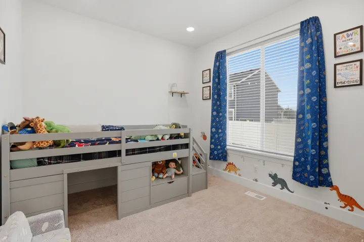 Bright room featuring a large window with horizontal blinds, neutral wall paint, and light-toned carpet flooring