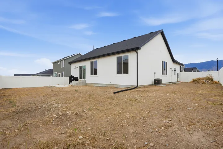 Expansive backyard featuring a white vinyl privacy fence, a concrete patio, and a mountain backdrop