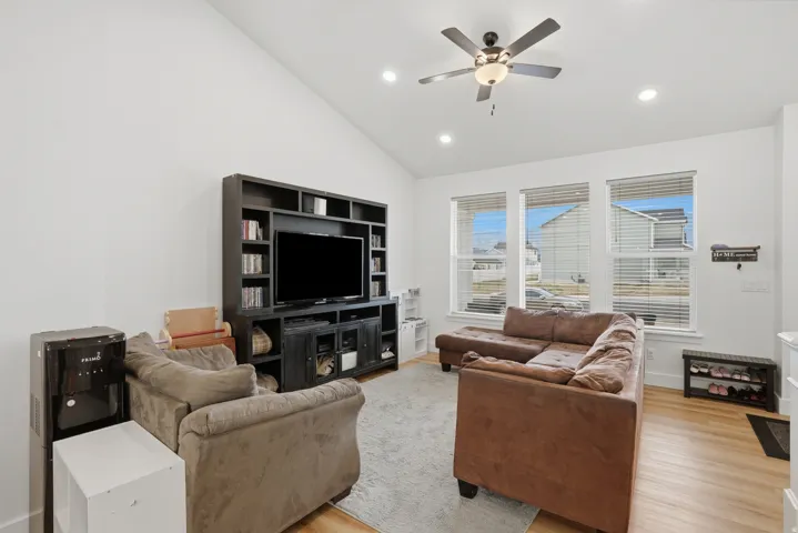 Spacious living area featuring a vaulted ceiling, recessed lighting, and a ceiling fan