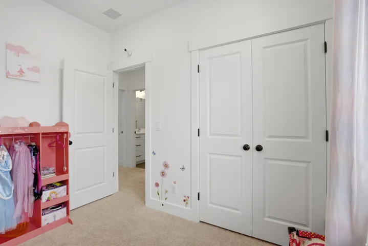 White interior with plush carpet flooring, showcasing a pair of paneled bifold closet doors with dark hardware