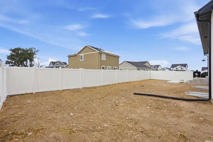 Expansive rear yard featuring a newly installed white privacy fence and a section of concrete patio