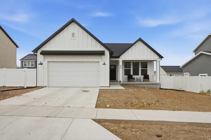 Contemporary farmhouse exterior featuring white board and batten siding, a dark pitched roof, and a covered front porch with columns