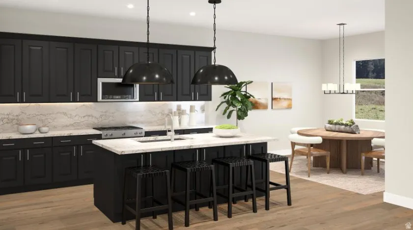 *Color scheme may differ*Open-concept kitchen featuring dark cabinetry with light stone-finish countertops and backsplash