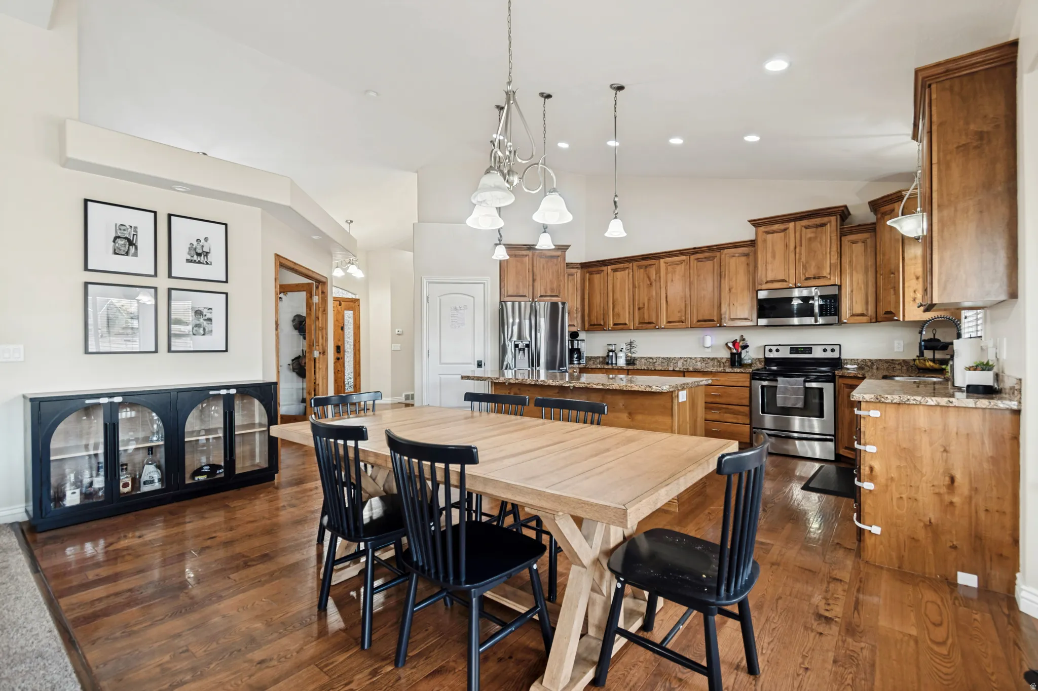 Open-concept kitchen and dining area featuring wood-finish flooring, recessed lighting, and a vaulted ceiling