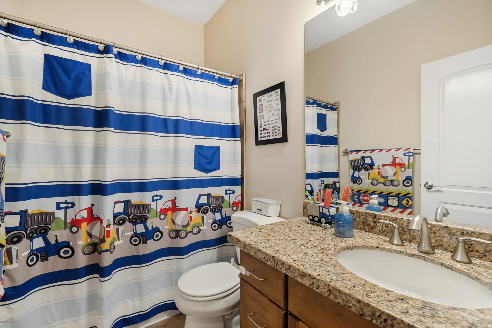 Bathroom featuring a vanity with a granite-style countertop, undermount sink, and brushed nickel fixtures
