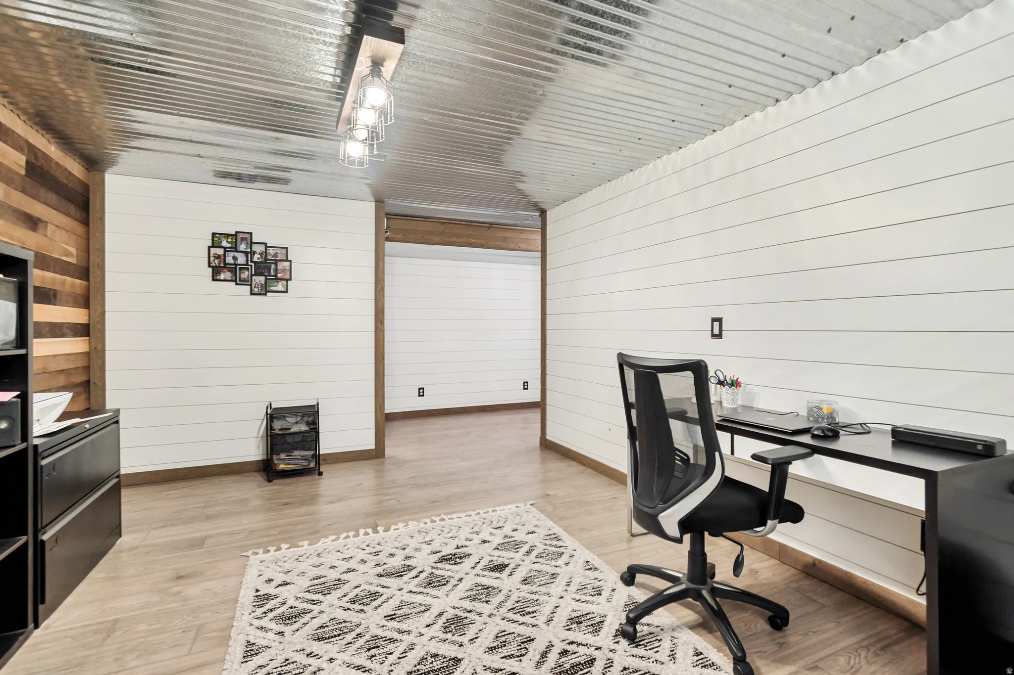 Open interior space featuring wood-finish flooring, white shiplap walls, and a corrugated metal ceiling