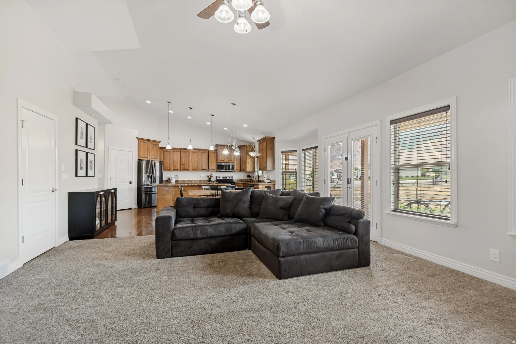 Open-concept living area featuring a vaulted ceiling with a ceiling fan, recessed lighting, and light-toned carpeting
