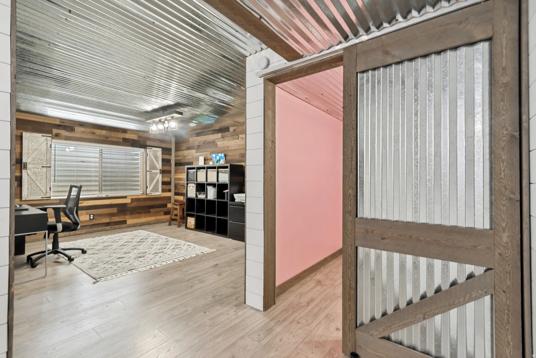 Corrugated metal ceiling and accent wall with wood-finish flooring