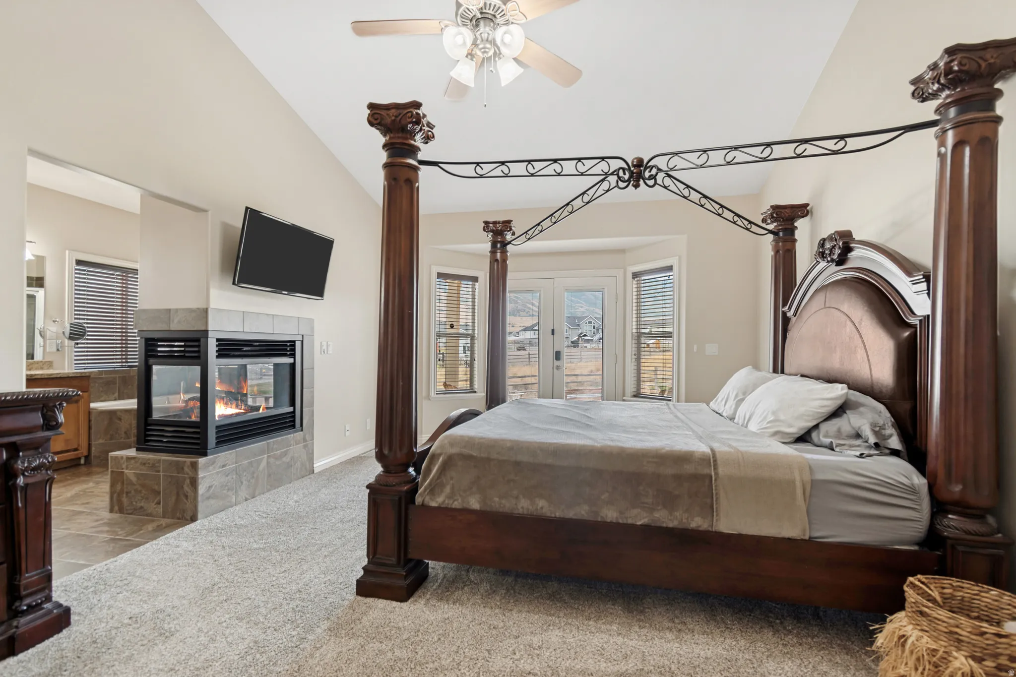 Spacious room featuring vaulted ceilings, a built-in three-sided fireplace with stone-tile surround, and plush carpeting