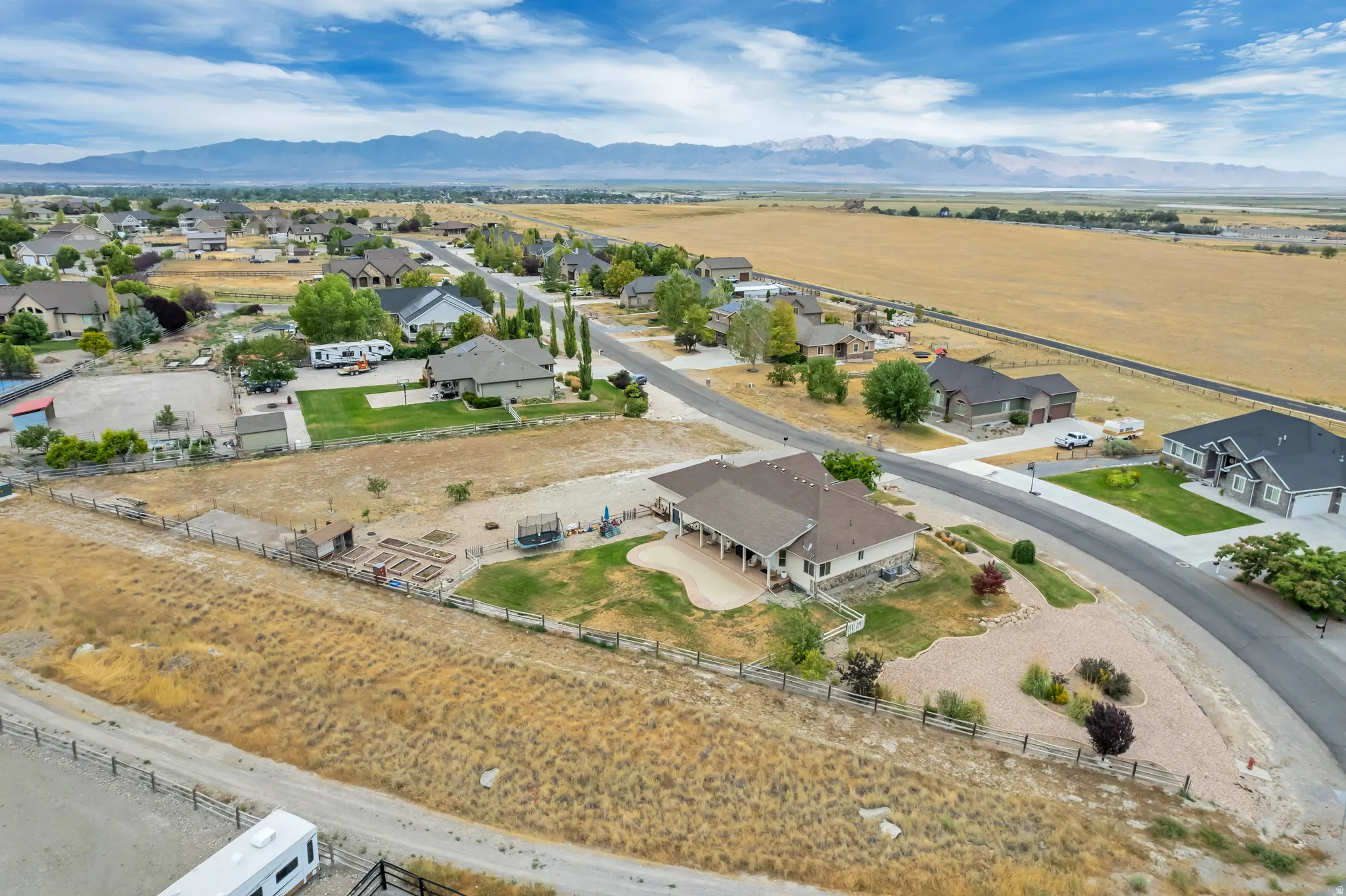 Expansive property featuring a paved driveway, a large rear patio, mature landscaping, and mountain scenery