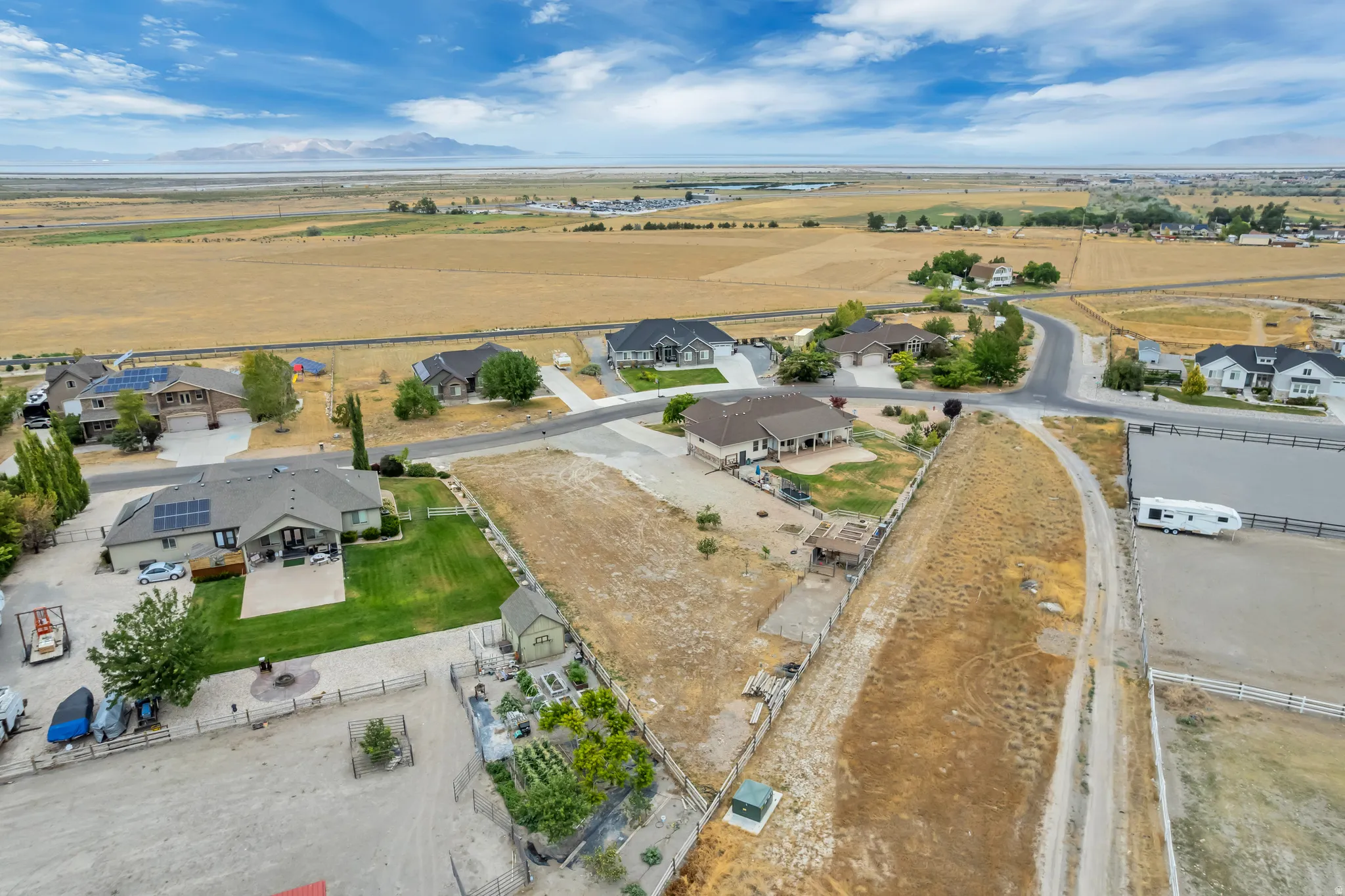 Expansive property featuring a large parcel of undeveloped land, several residential structures, a private dirt access road, and an equestrian arena