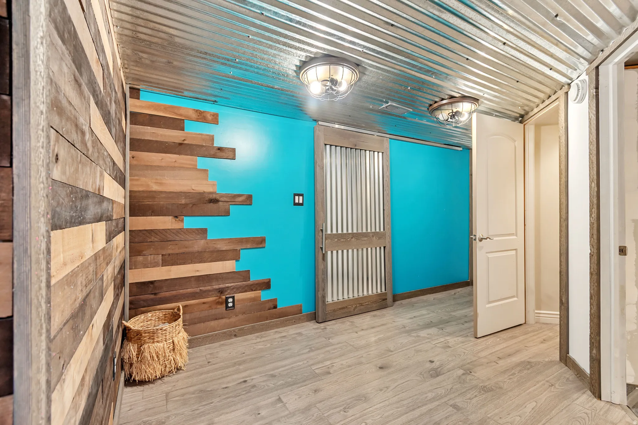 Corrugated metal ceiling paired with a vibrant accent wall and wood-finish flooring