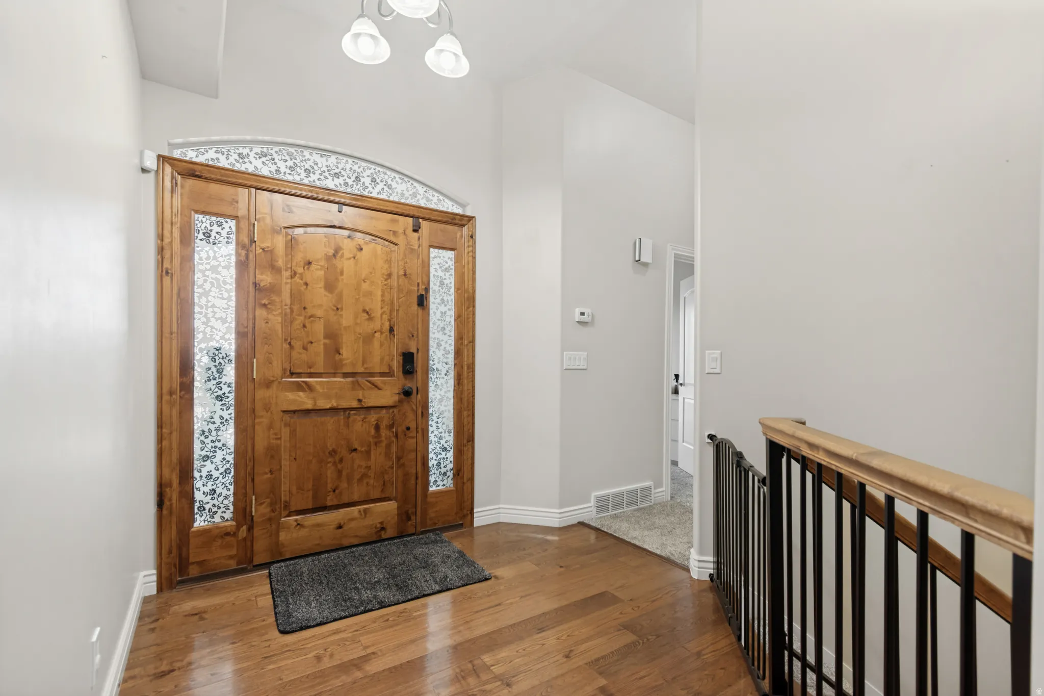 Entryway featuring a solid wood front door with decorative glass sidelights and transom