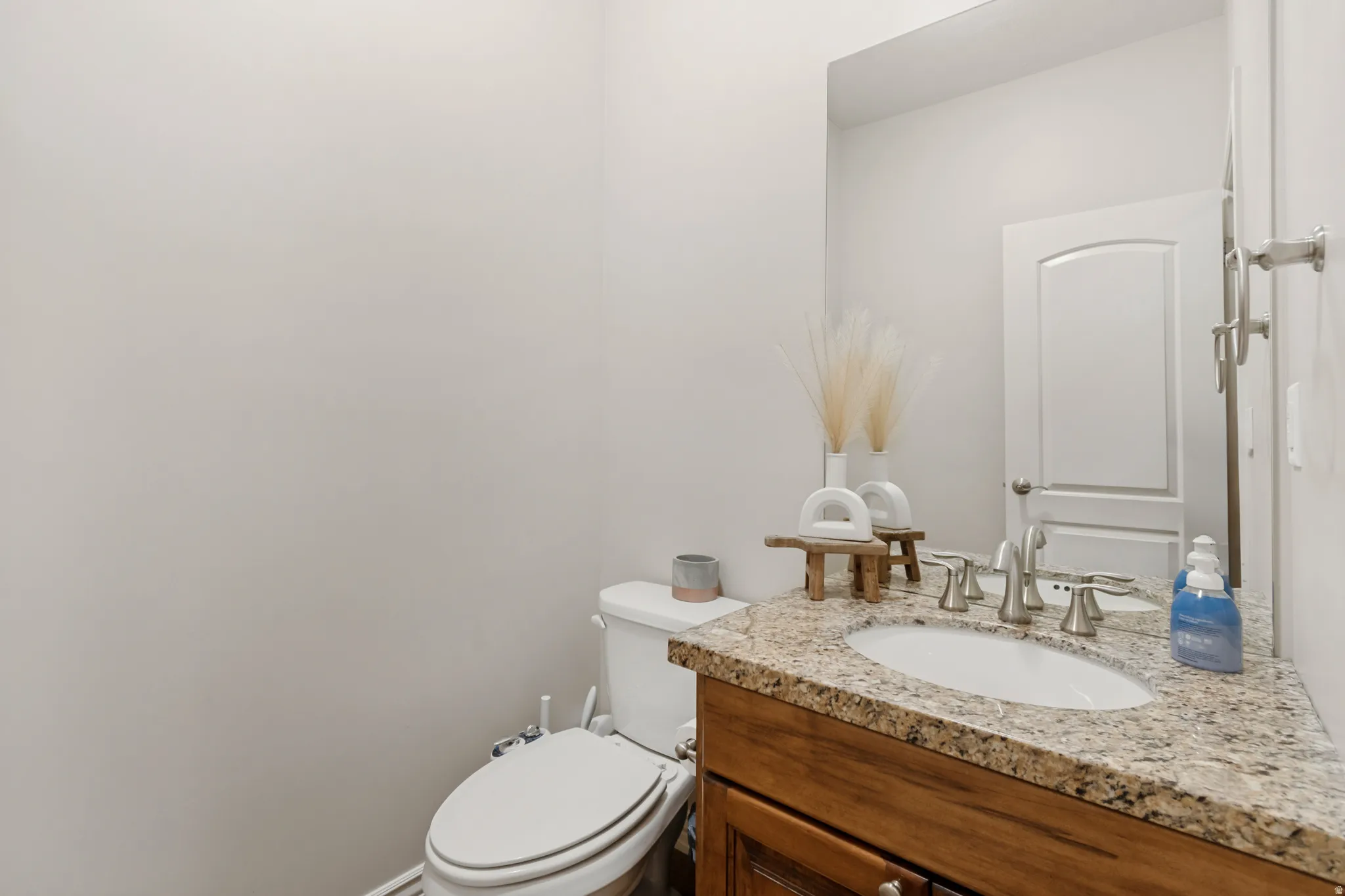 Bathroom vanity featuring a granite countertop, undermount sink, and brushed nickel fixtures