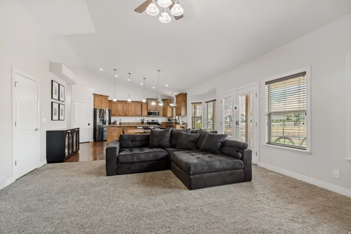 Open-concept living area featuring a vaulted ceiling with a ceiling fan, recessed lighting, and light-toned carpeting