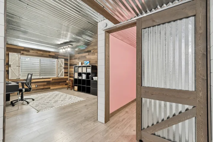 Corrugated metal ceiling and accent wall with wood-finish flooring