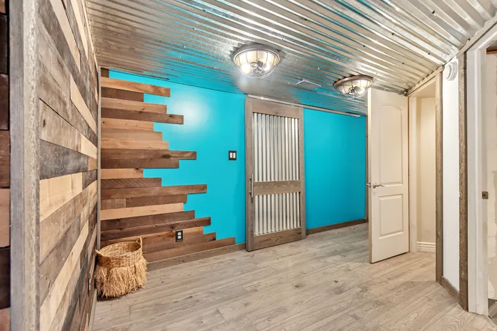Corrugated metal ceiling paired with a vibrant accent wall and wood-finish flooring