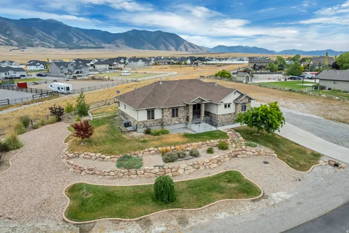 Stone and stucco exterior with a multi-level roofline, featuring a concrete driveway and an additional gravel parking area