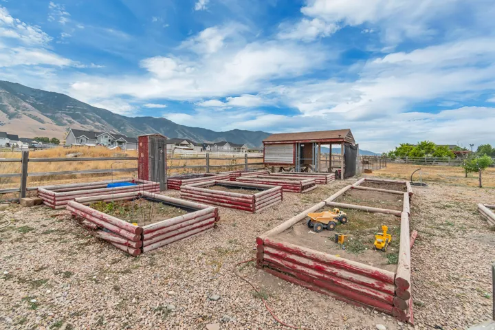Multiple raised garden beds, a rustic storage shed, and a wooden fence define this outdoor space