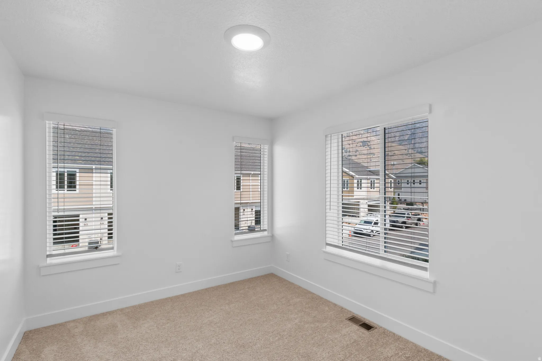 Neutral white walls with recessed lighting and neutral carpet