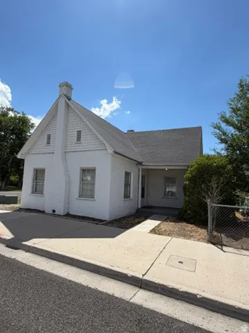 White stucco exterior featuring a gabled roofline and prominent chimney