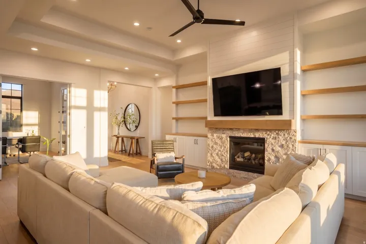 Living area featuring a stone-clad fireplace with wood mantle, built-in shelving, wood-finish flooring, and recessed lighting