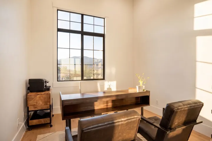 Room featuring a large grid-pattern window with mountain scenery, light wood-finish flooring, white baseboards, and neutral wall tones
