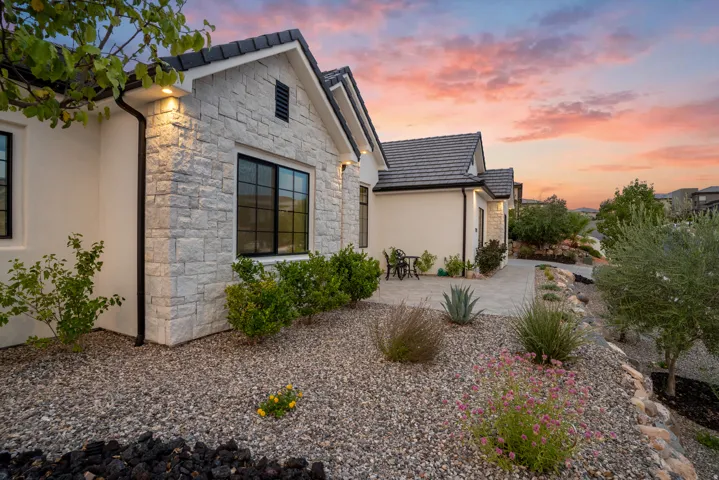 Stucco and stacked stone exterior featuring black-framed windows, a dark tile roof, and integrated soffit lighting
