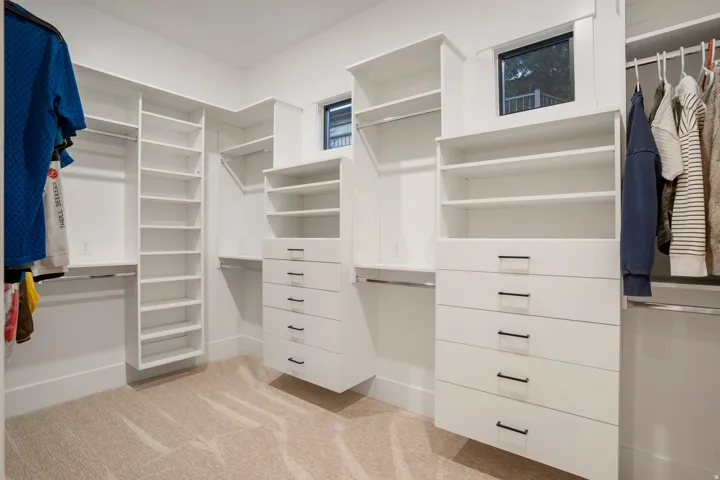 Integrated custom closet system featuring multiple hanging rods, extensive shelving, and built-in drawer units with matte black hardware