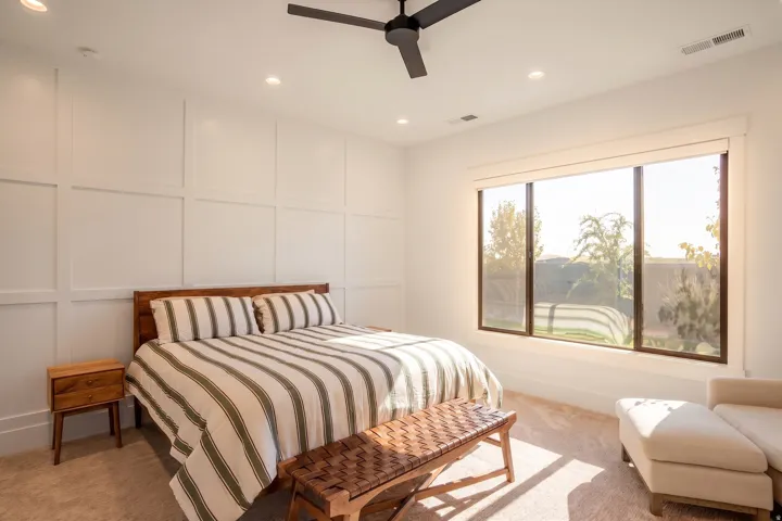 Bright bedroom featuring a large picture window, board and batten accent wall, recessed lighting, and a ceiling fan