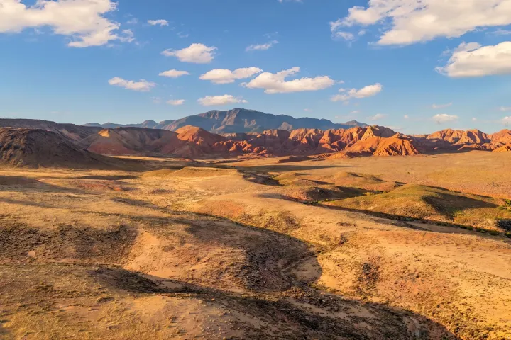 Expansive desert landscape featuring rolling hills and distant mountains